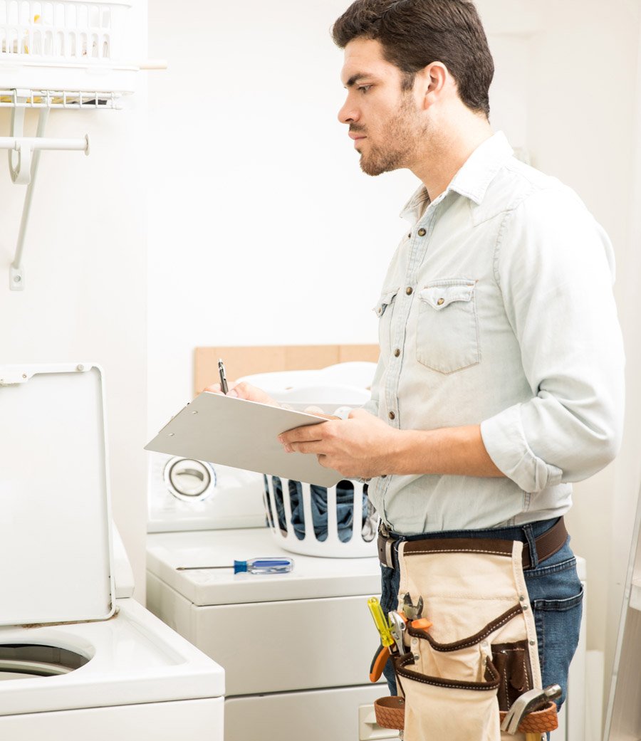 young male electrician doing some repairs laundry room looking washing machine (1)